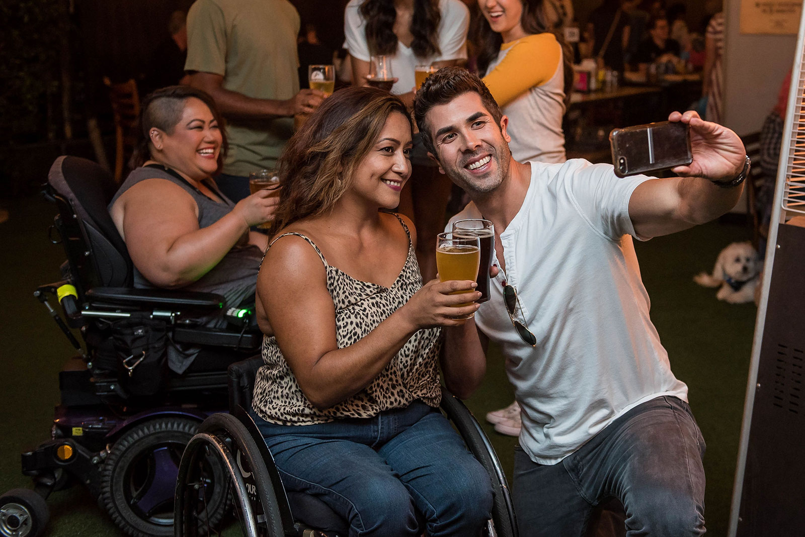 Two wheelchair users with friends at a bar.